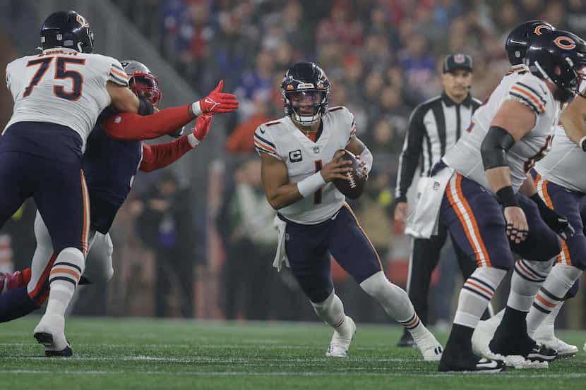 Chicago Bears quarterback Justin Fields (1) runs through a hole in the line during the first...