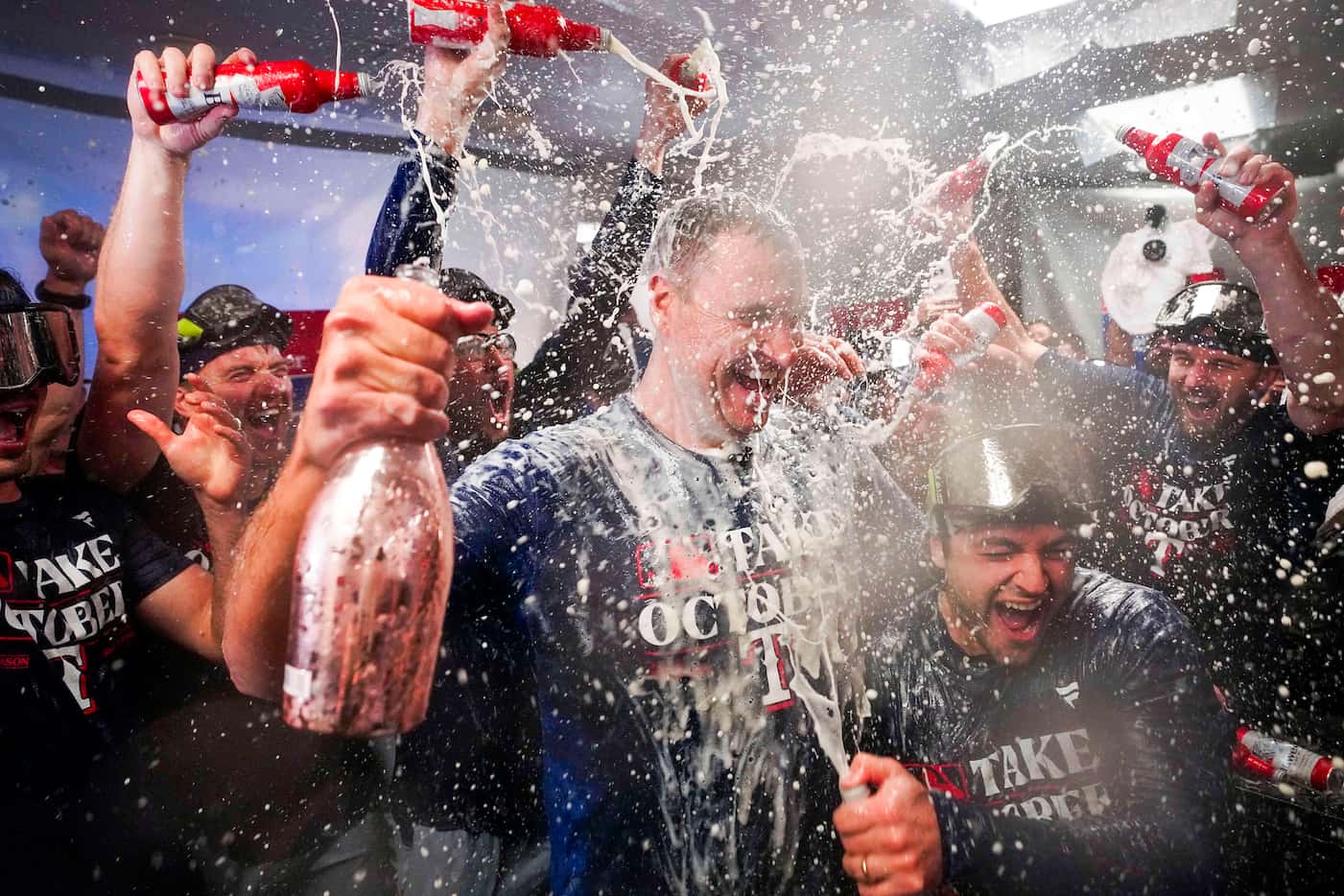 Texas Rangers general manager Chris Young is doused with beer and champagne by players in...