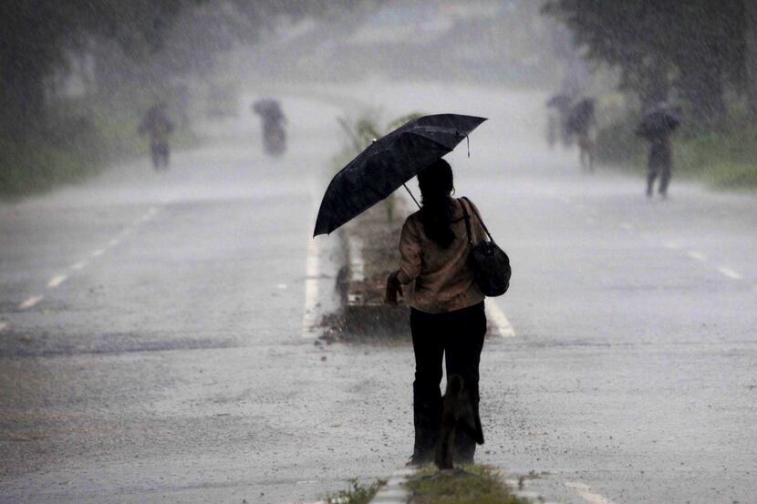 An Indian woman holds an umbrella as she heads towards a cyclone shelter near Chatrapur in...