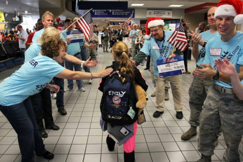 Volunteers in Santa hats and camouflage lined Terminal C on Friday at D/FW Airport to greet...