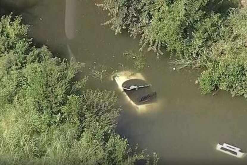 A car lies submerged in a creek Tuesday morning near Interstate 635 and Freeport Parkway in...