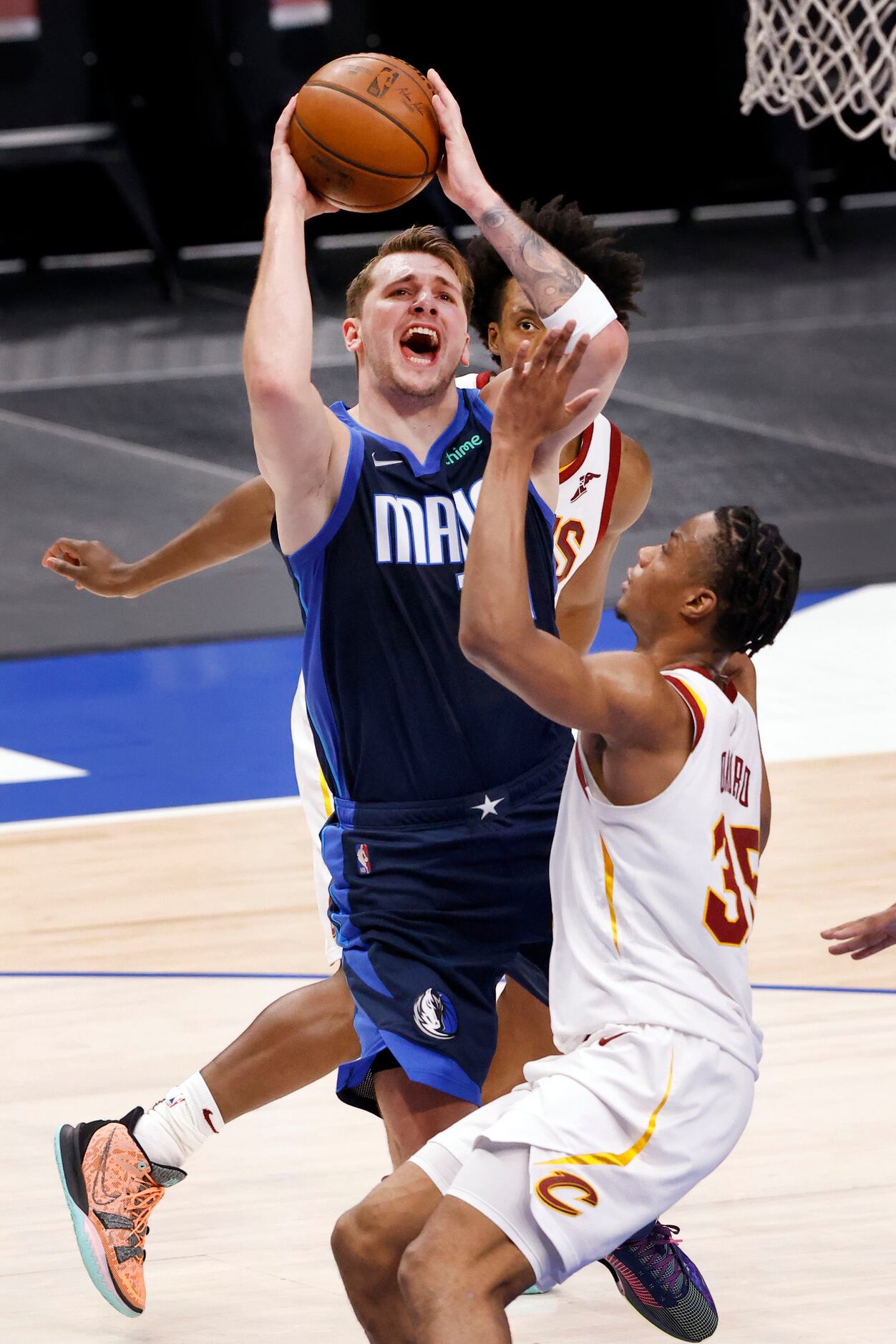 Dallas Mavericks guard Luka Doncic (77) splits a pair of Cleveland Cavaliers defenders for a...