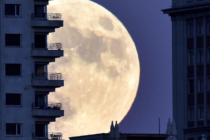 A man stands on a balcony of a building of Madrid as the moon rises in background, on...