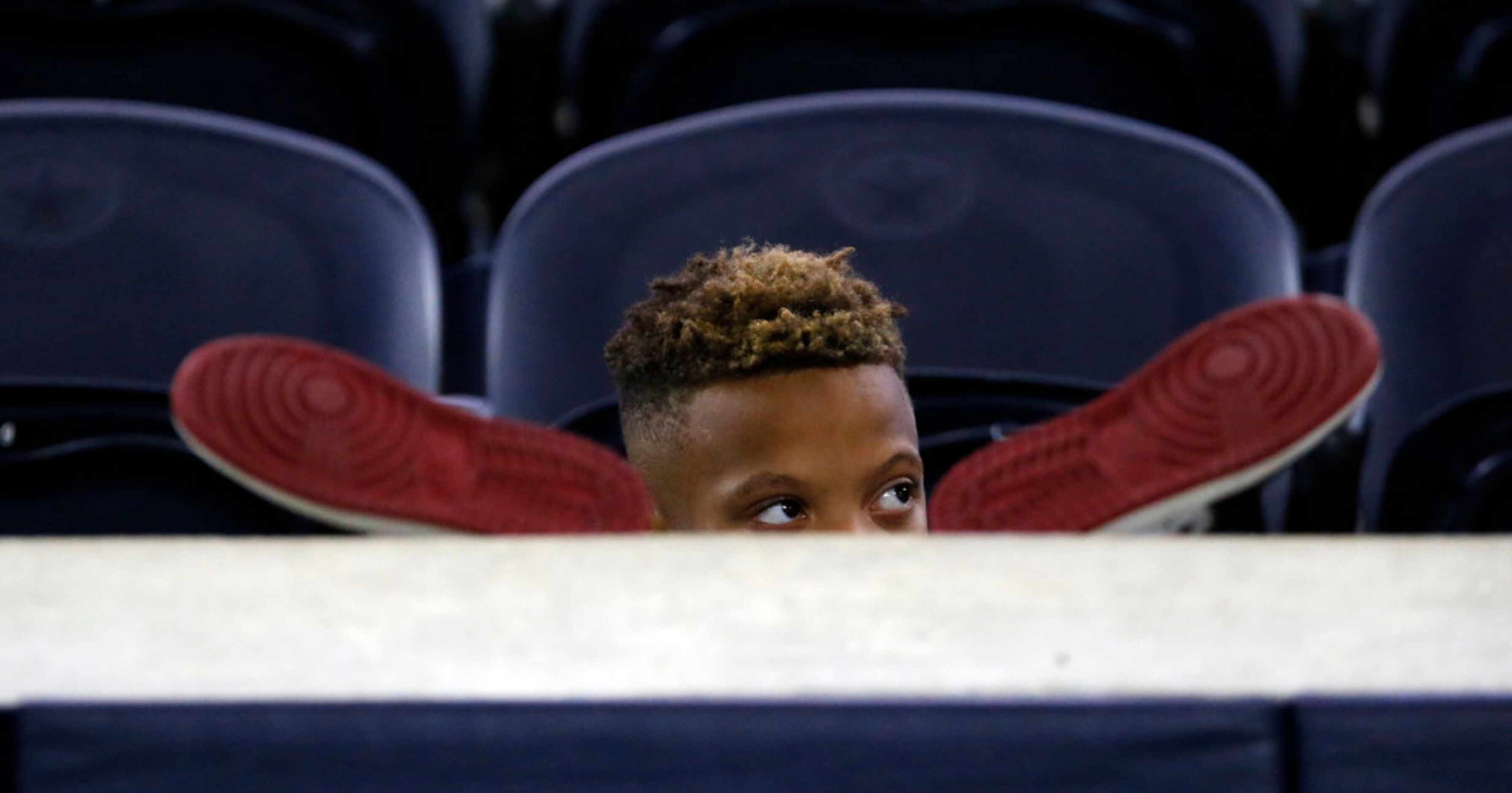 Ryland Smith, 9, watches South Oak Cliff's pregame warmup from between his athletic shoes...