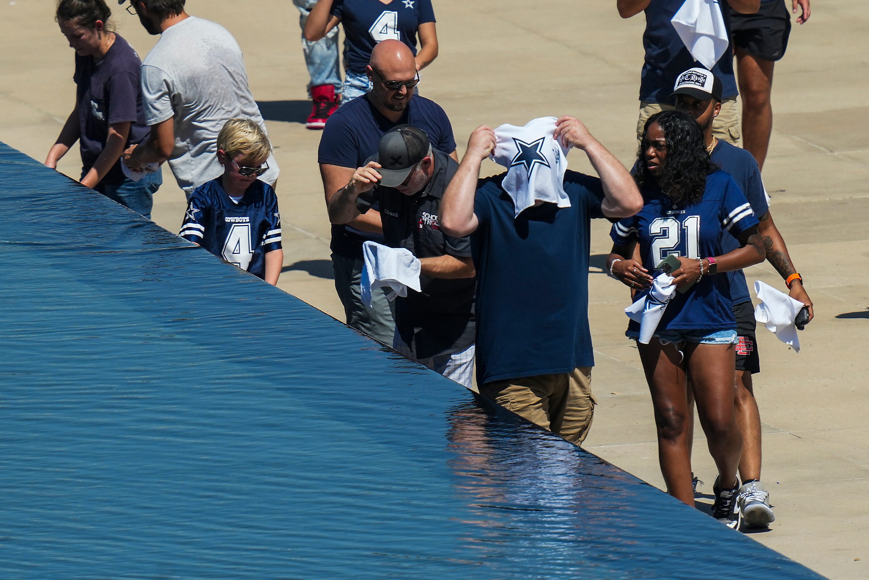 Dallas Cowboys fans use complimentary towels to cool off in a fountain outside the stadium...