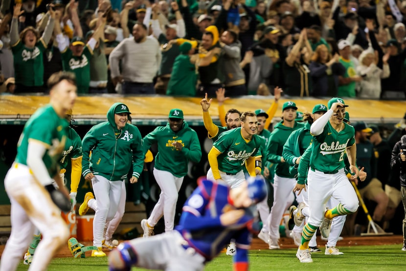 Oakland Athletics players pour out of the dugout to celebrate after defeating the Texas...