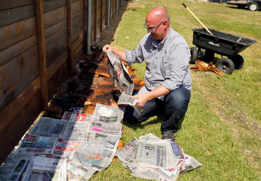 Daniel Cunningham drapes wet newspaper over homemade compost and wet cardboard.