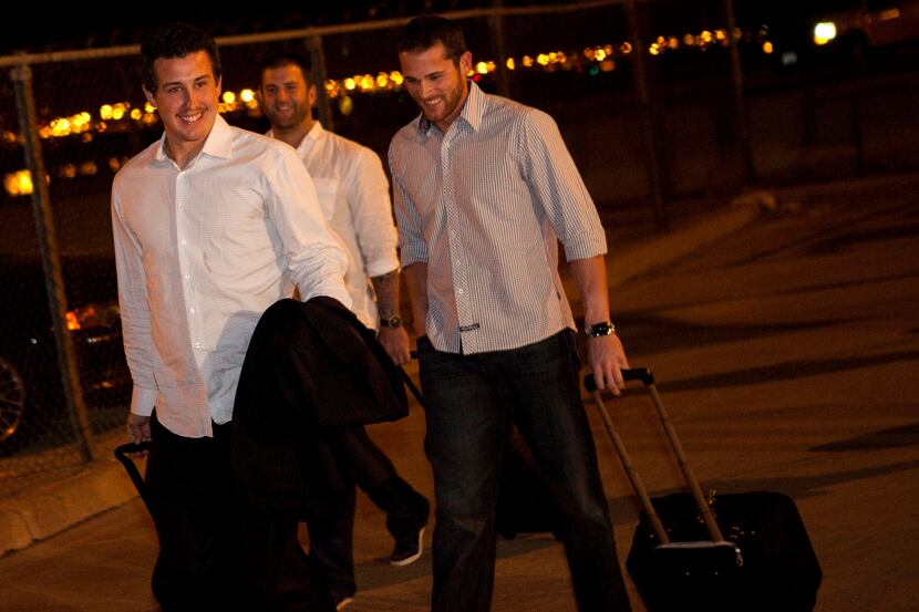 Rangers players (from left) Derek Holland, Mike Napoli and Craig Gentry walk from the plane...