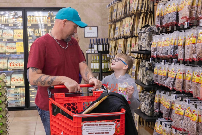 Derek Eakins of Ottumwa, Iowa listens as his son Dalton Eakins, 8, asks about buying a snack...