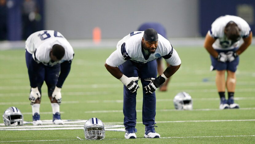 Dallas Cowboys tackle Tyron Smith (77) stretches at the end of practice during training camp...