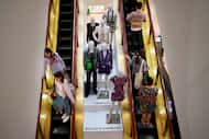 Shoppers move past displays of designer clothes at the Neiman Marcus department store in...