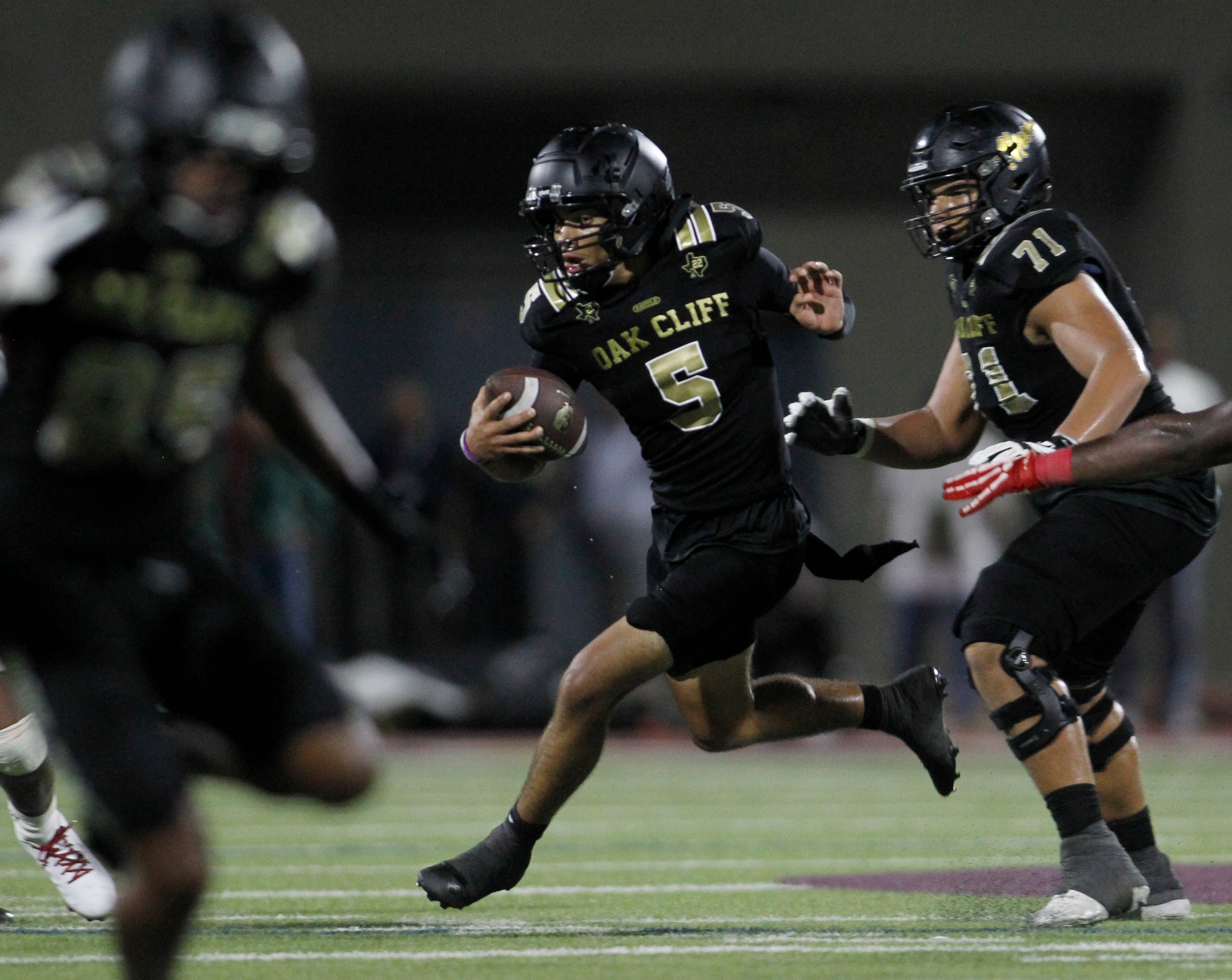 South Oak Cliff quarterback Reggie McNeal (5), center, sprints out of the backfield and into...