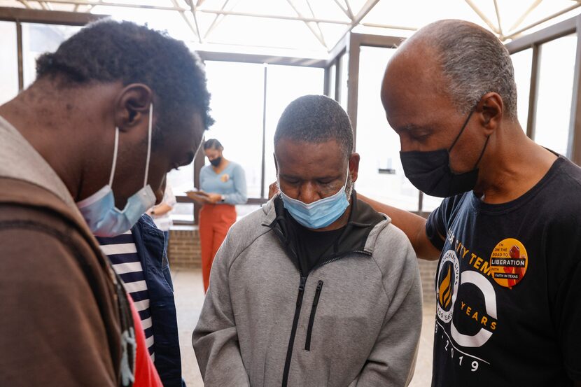 Carey McMorton, City Temple Seventh Day Adventist Church elder (right), prays over Robin...