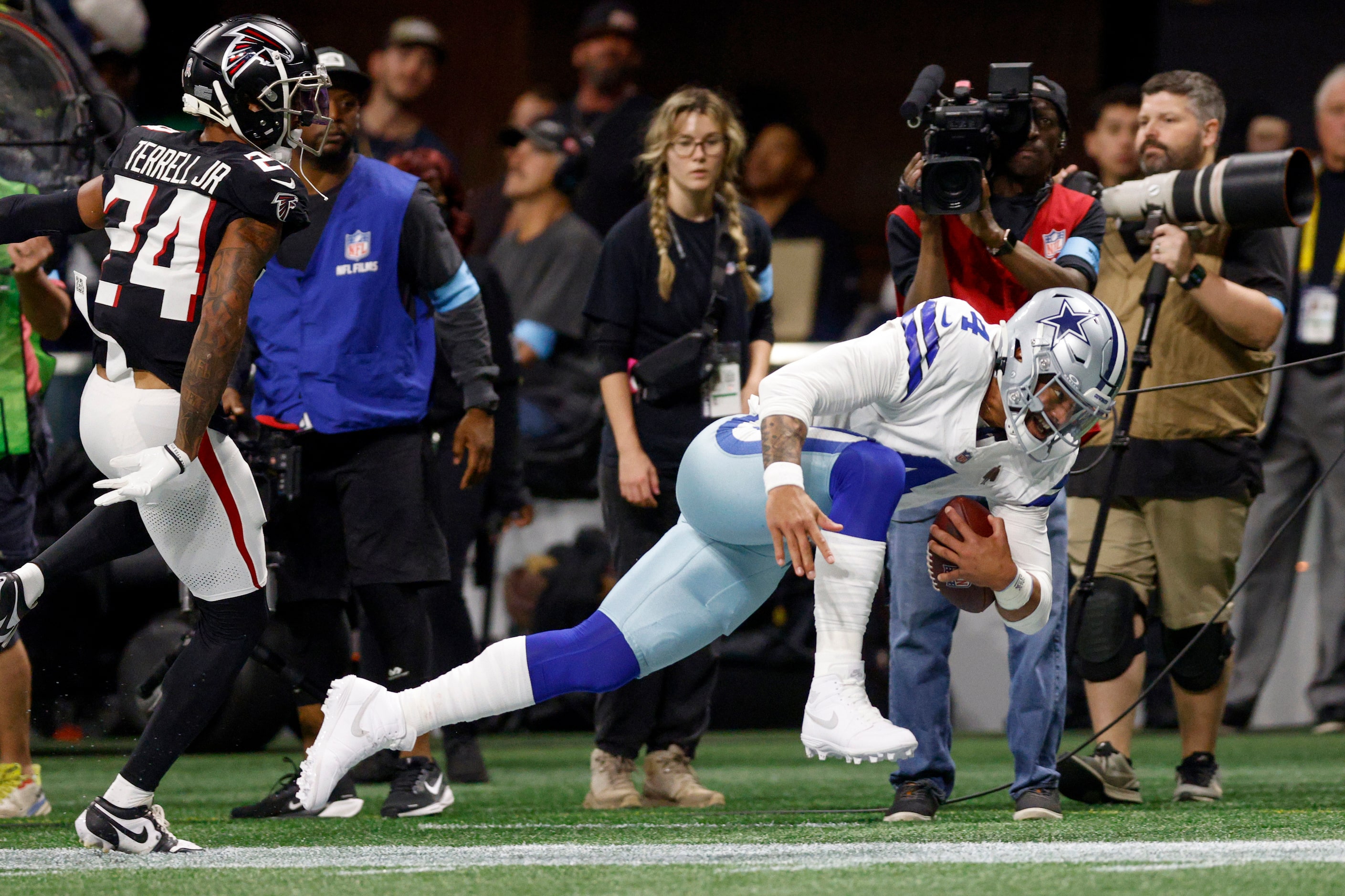 Dallas Cowboys quarterback Dak Prescott (4) falls to the ground after being pushed out of...