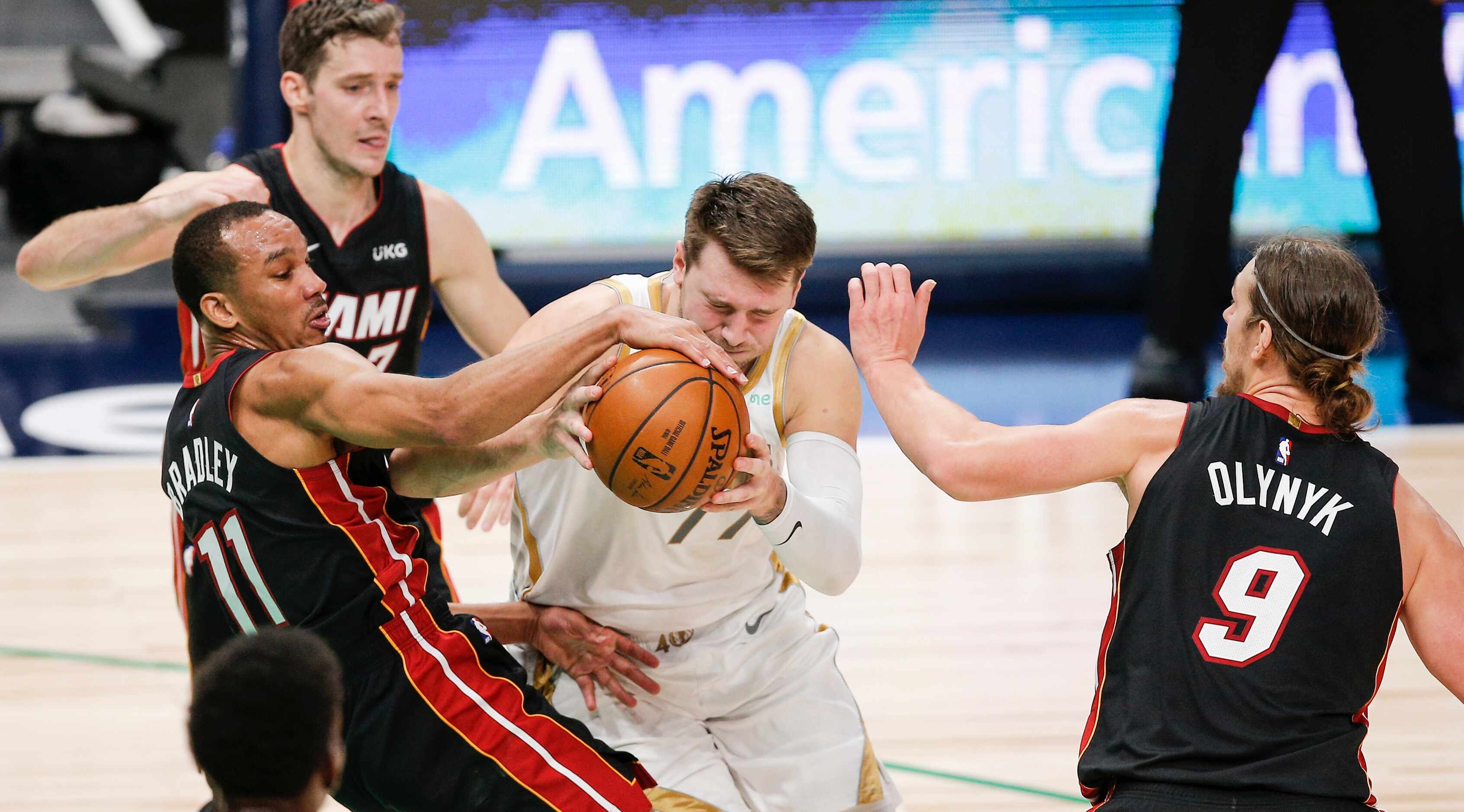 Dallas Mavericks guard Luka Doncic, center, battles Miami Heat guards Avery Bradley (11),...