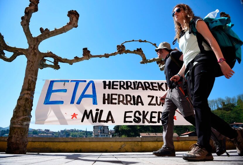 A couple walks past a banner that reads in Basque "ETA with the people, the people with you....