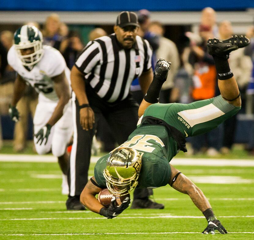 Baylor running back Shock Linwood (32) tumbles to the ground after being tripped up during...