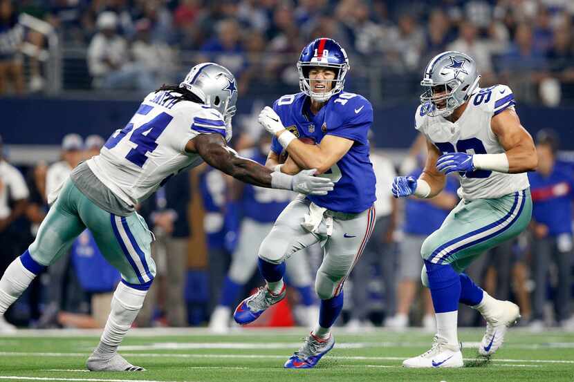 New York Giants quarterback Eli Manning (10) is hit hard and sacked by Dallas Cowboys...