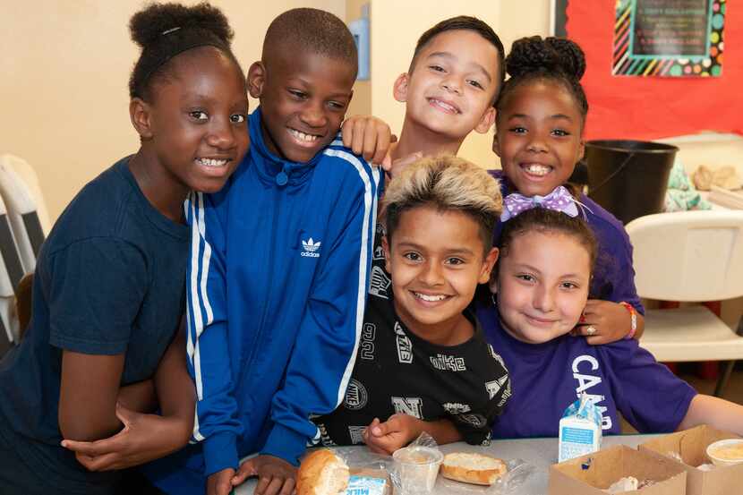 Six children smile and enjoy a snack provided by the North Texas Food Bank.