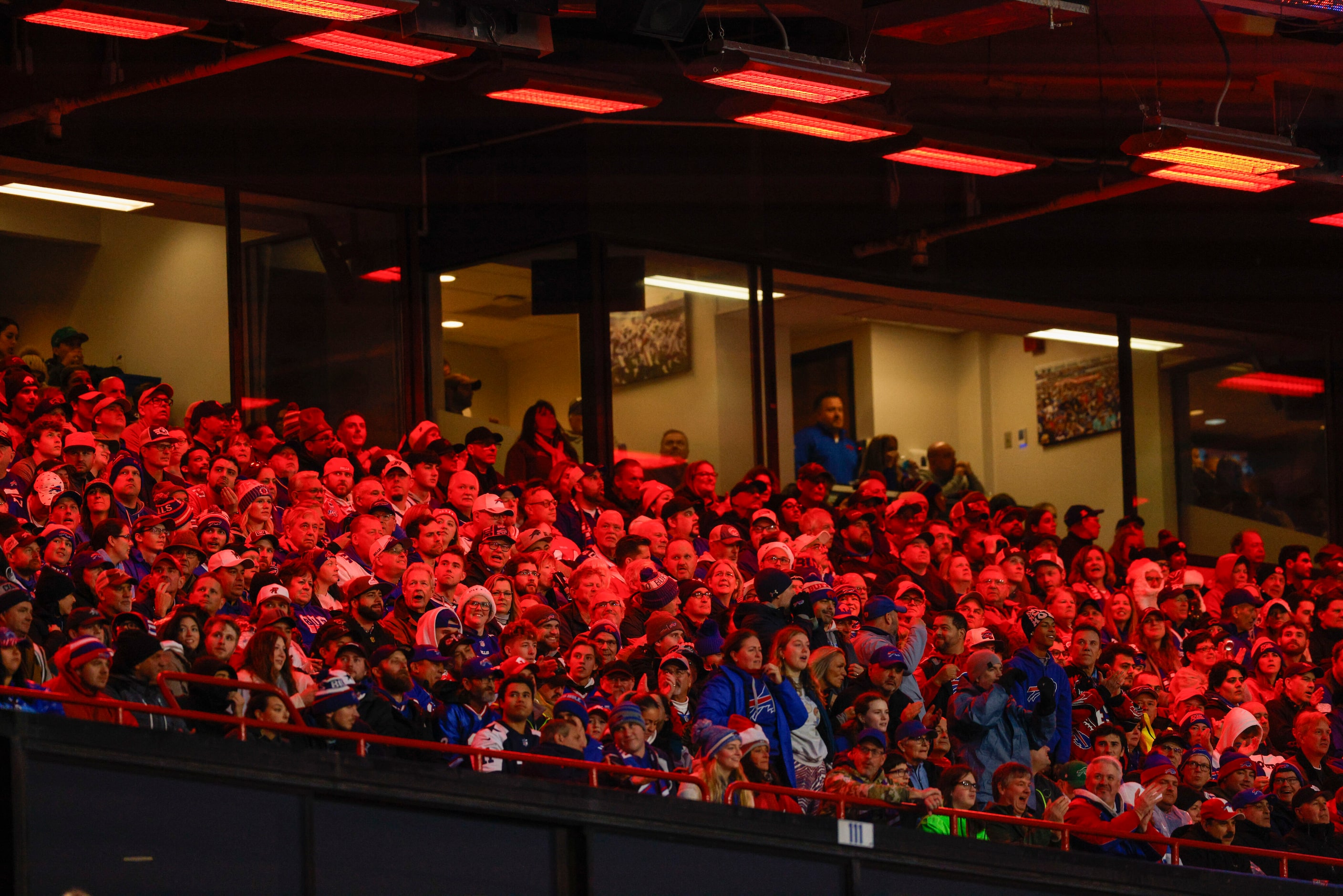 Fans sit underneath heat lamps during the first half of an NFL game between the Dallas...