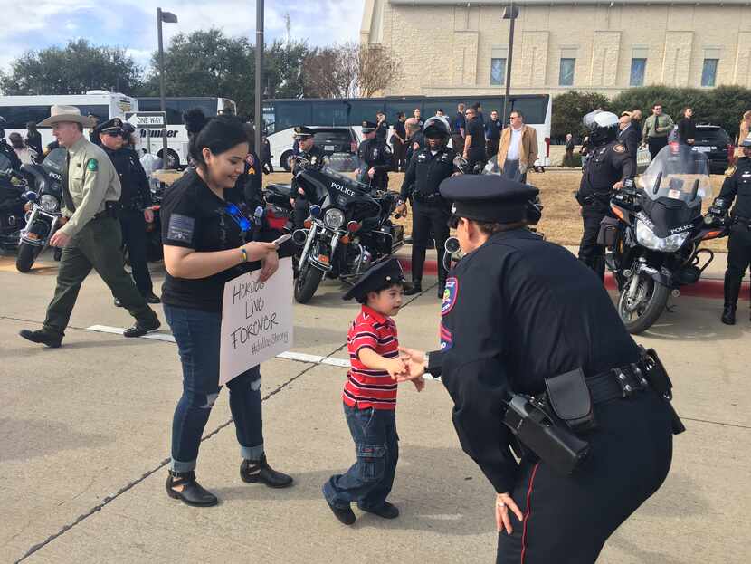 Jayden Morales, trailed by his aunt Melissa Morales, shakes hands with a police officer at...
