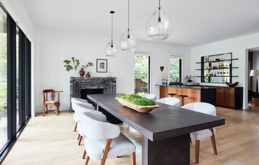 Contemporary dining room cozied up with a fireplace on one end and a chic wet bar in a...