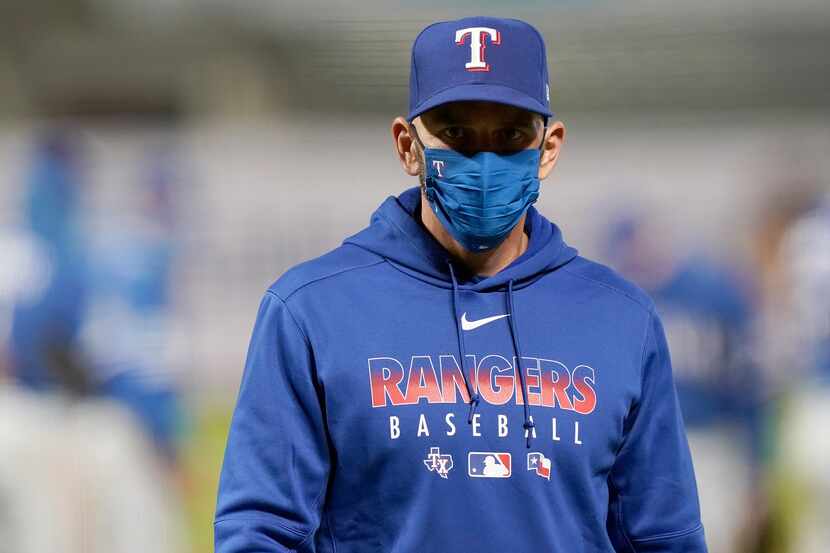 Rangers manager Chris Woodward walks back to the dugout after making a pitching change...
