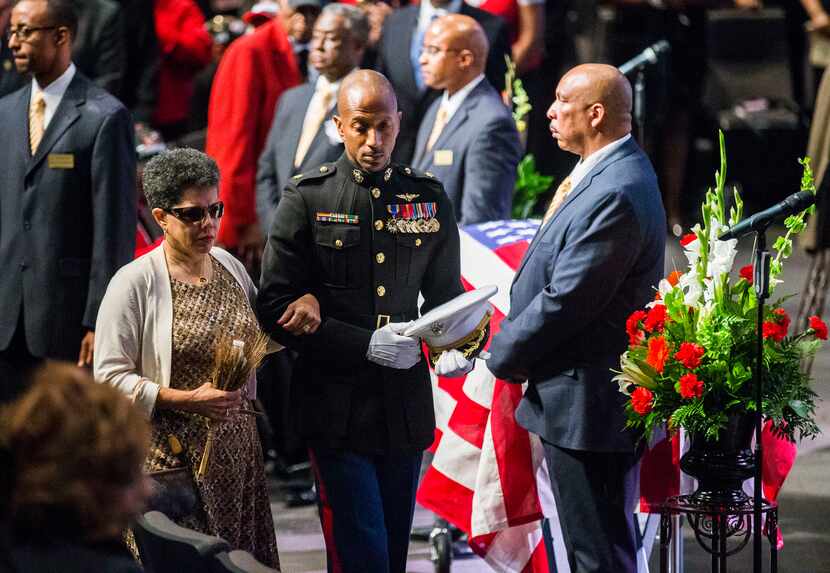 U.S. Marine Major Alejandro House, retired, escorts Gwenelle Johnson Spann during funeral...
