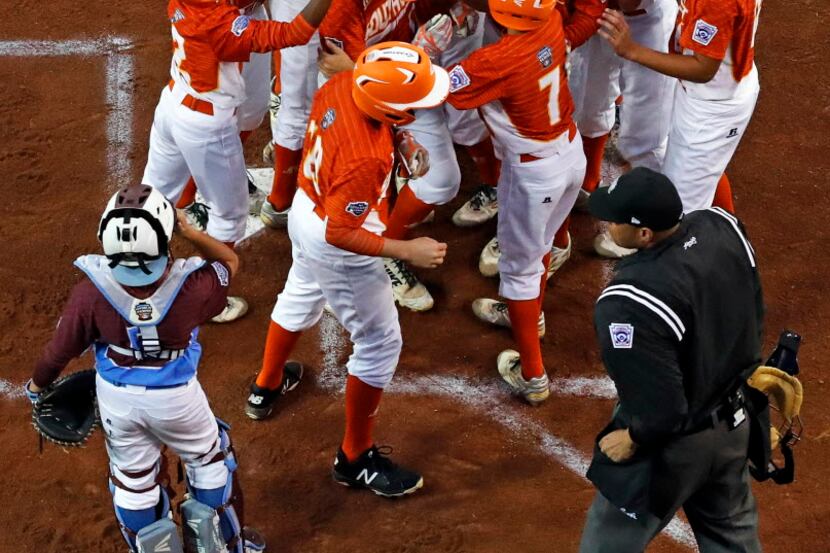 Collin Ross of the Lufkin Little League All-Stars is mobbed by teammates after hitting a...