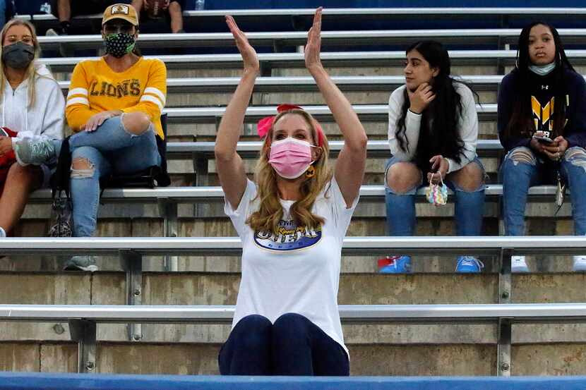 McKinney resident Cindy Philosfsky (center) dons a mask and practices social distancing as...