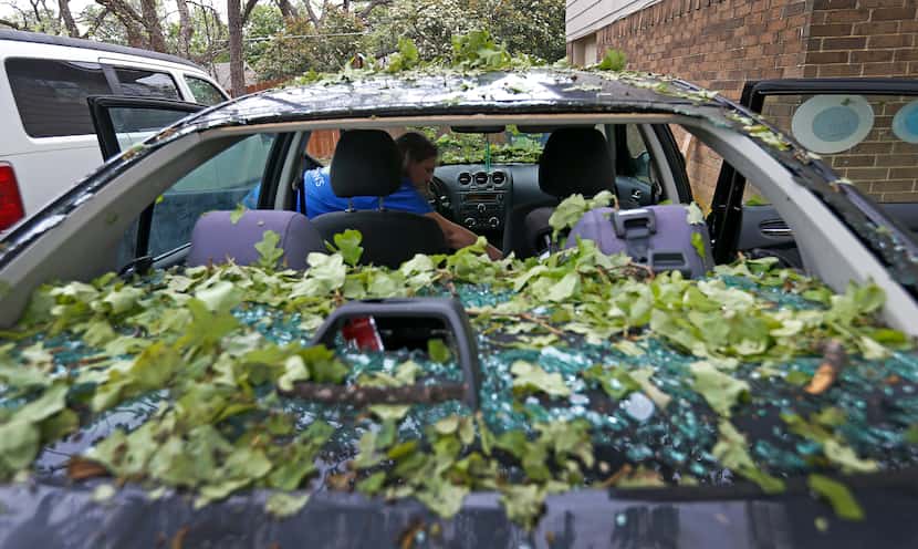 Tara Shadoan takes her belongings before the insurance company tows her car damaged by last...