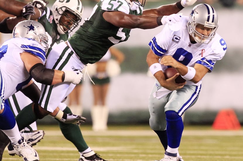 Dallas Cowboys quarterback Tony Romo (9) tries to avoid New York Jets linebacker Bart Scott...