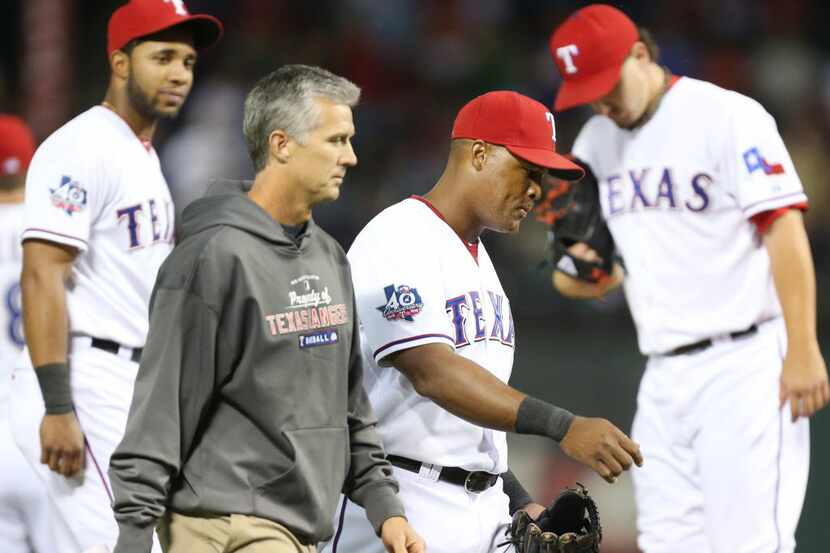 FILE - Texas third baseman Adrian Beltre is escorted off the field by trainer Kevin Harmon...