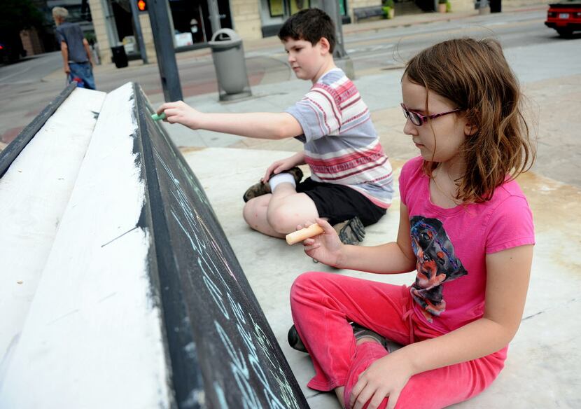Kennedy, 9, and brother Griffin, 12,  from East Dallas, draw on the chalk boards provided by...