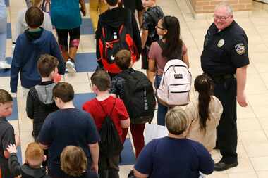 McKinney police school resource officer Chris Golden smiles at students as they make their...