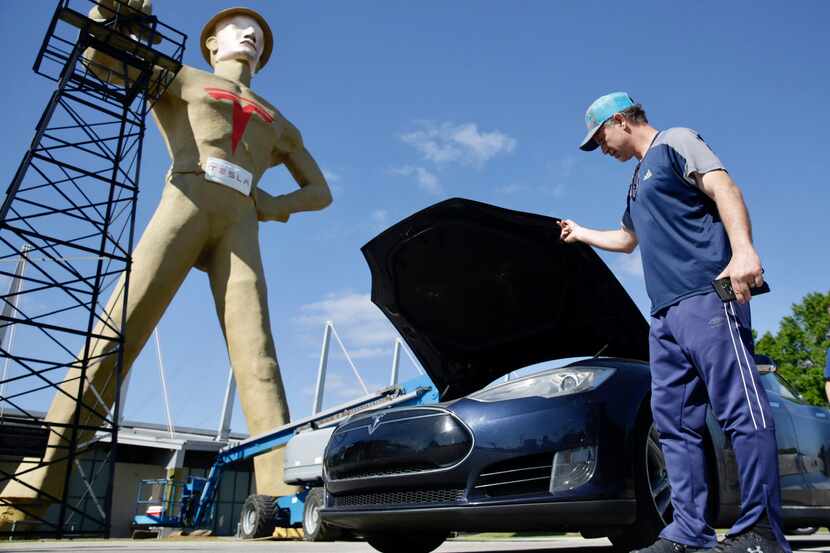 Andrew Nelson lifts the hood of his Tesla Model S in front of the Golden Driller as it gets...