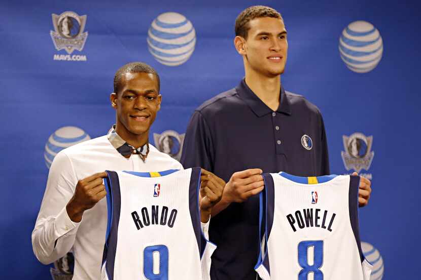 Rajon Rondo (left) and Dwight Powell hold their new Dallas Mavericks jerseys during a press...
