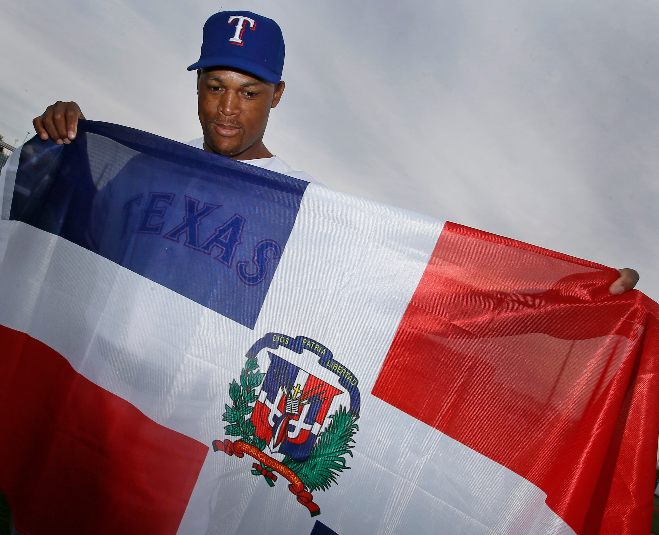 Texas third baseman Adrian Beltre poses with the Dominican republic flag at photo day during...