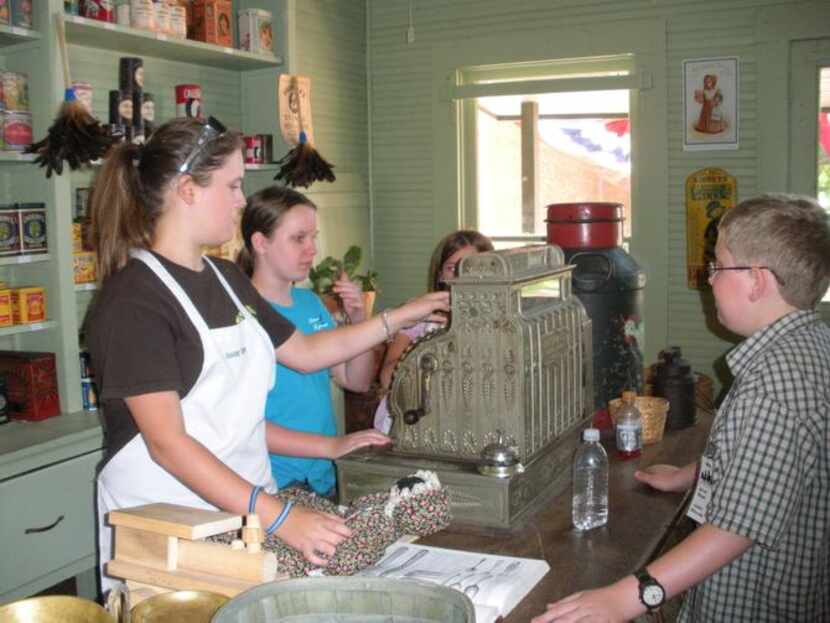 
Junior Historians show young shoppers how to use an antique cash register at Dallas...