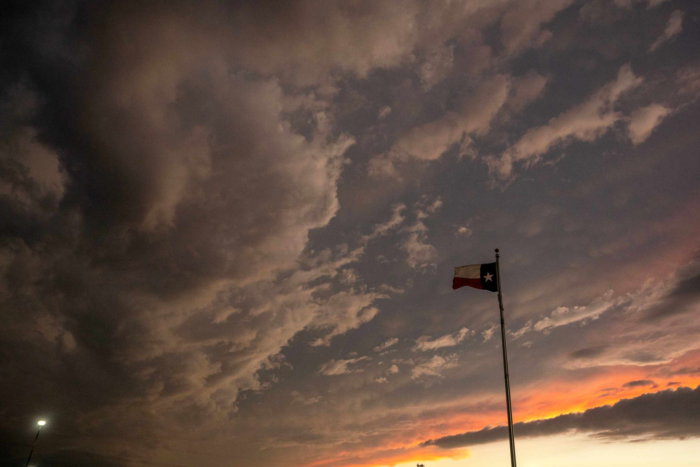 Storm clouds gather over a Texas flag outside Forester Field during a lightning delay before...
