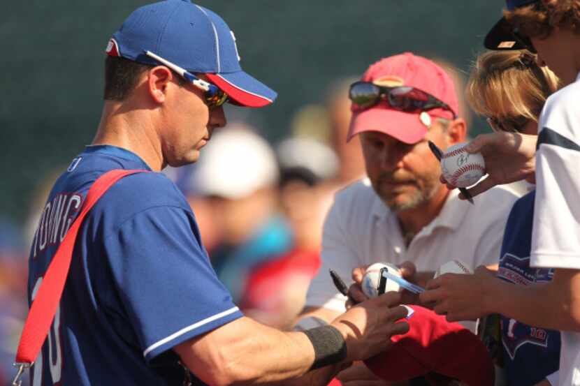 Texas Rangers third baseman Michael Young (10) signs autographs  for fans during their...