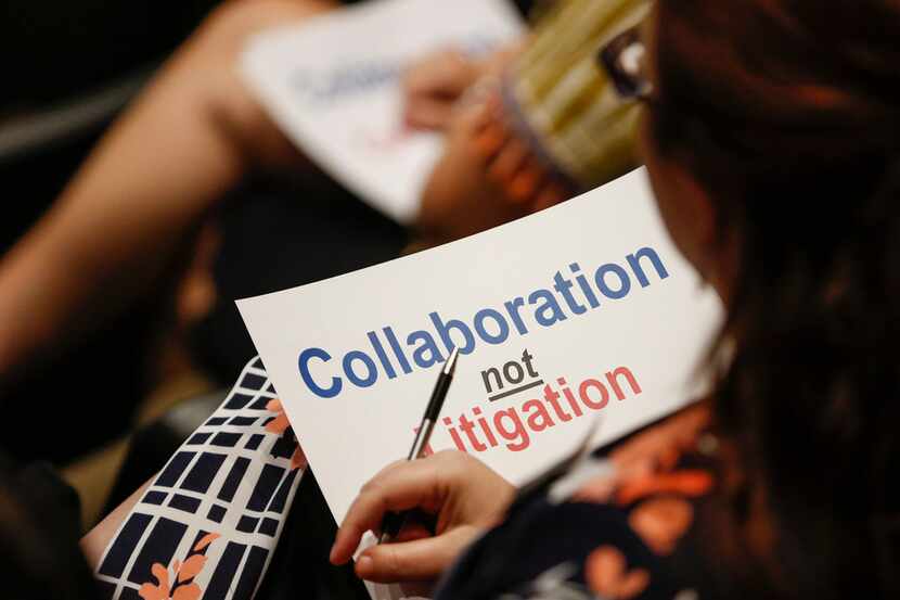 A citizen holds a sign that reads "Collaboration not Litigation" during a joint meeting of...