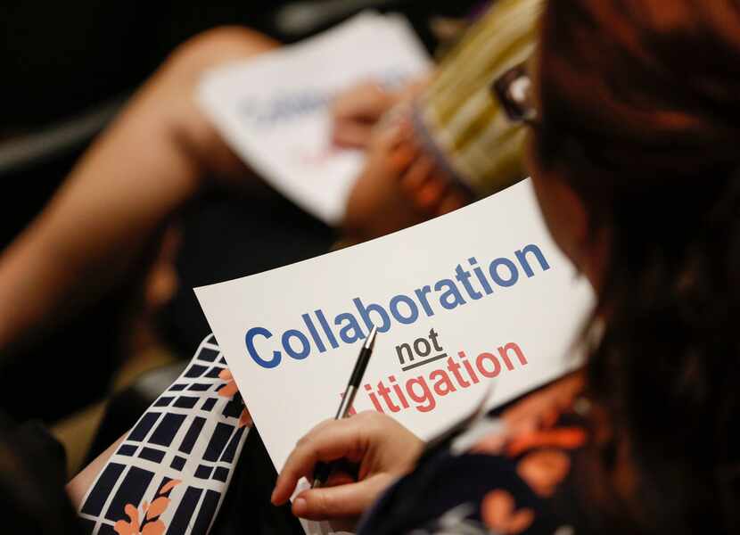 A citizen holds a sign during Monday's joint meeting of the Plano City Council and the...