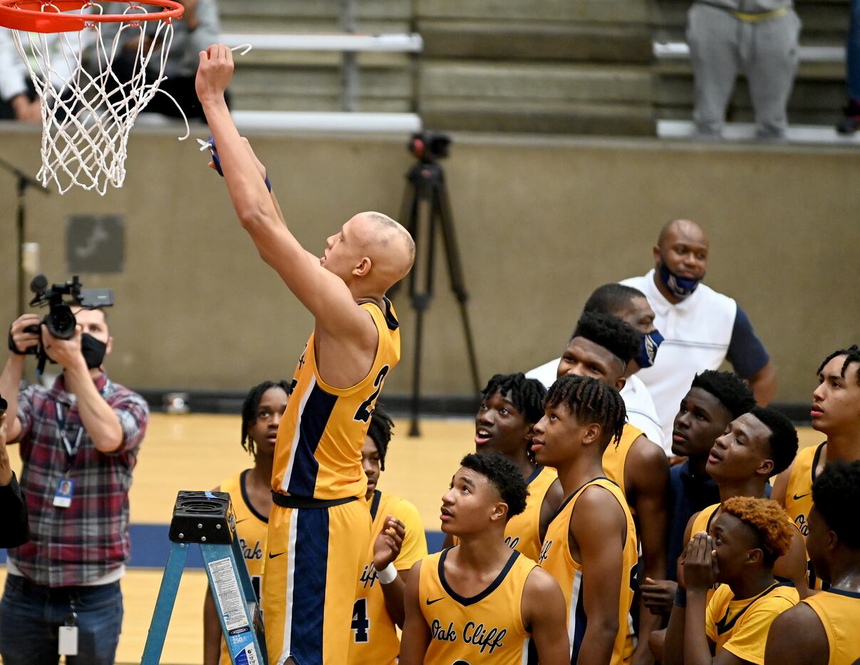 Teammates watch as Faith Family’s Jordan Walsh cuts down a piece of net after their win of a...