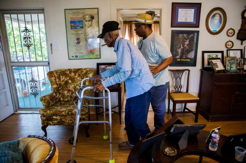  Richard Overton is escorted by family friend Martin Wilford through his living room to the...