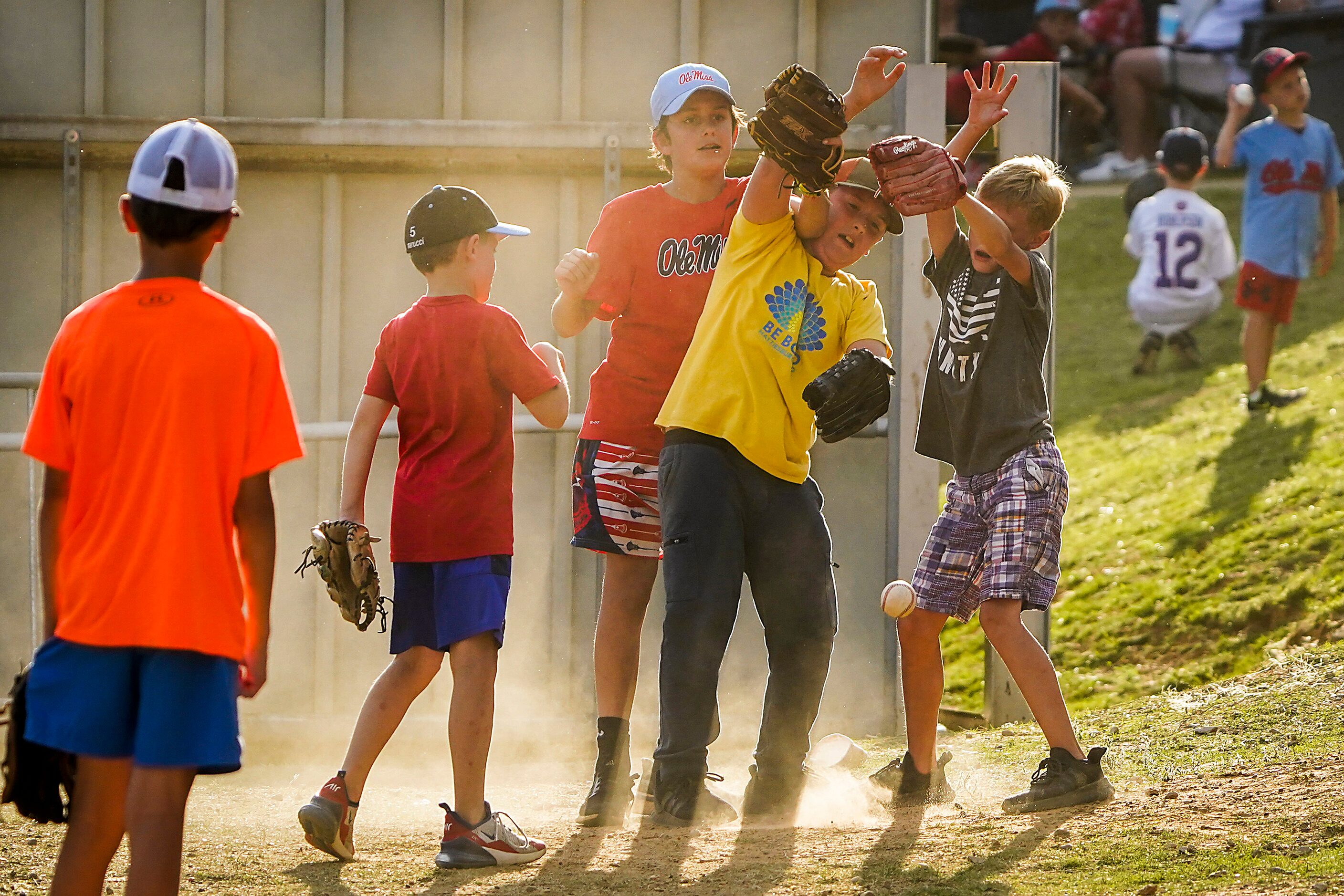 Youngsters reach for a baseball while playing just over the outfield fence during an NCAA...