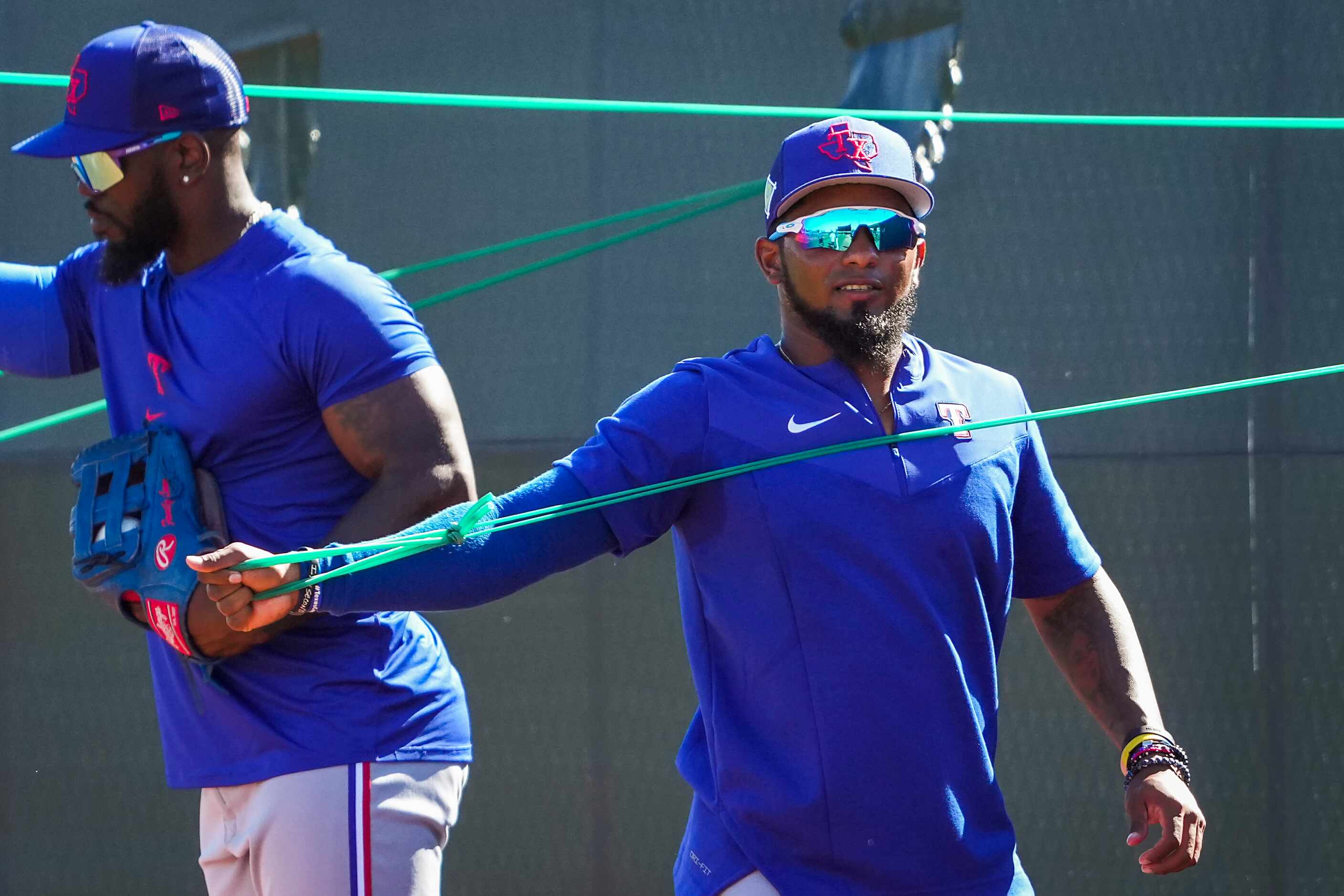 Texas Rangers infielder Yonny Hernandez (front) and outfielder Adolis García stretch using...