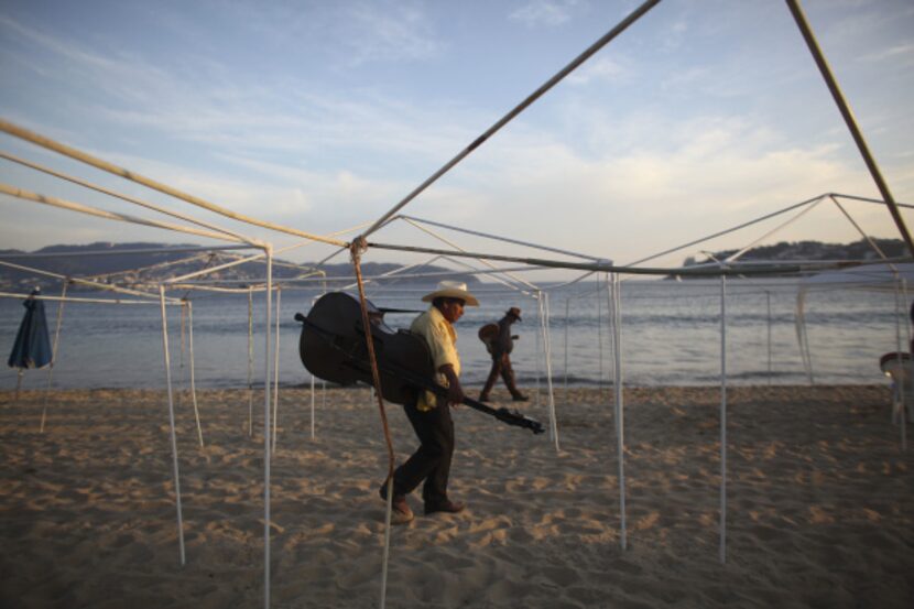 A couple of musicians look for clients willing to pay for a song at an empty Papagayo beach...