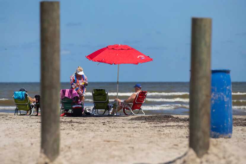Beachgoers relax near the beach access point on Buccaneer Boulevard in the Pirates Beach...