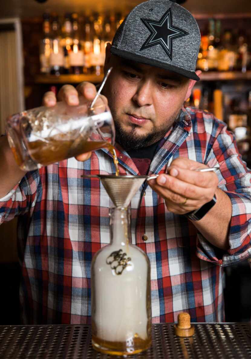 Mixologist Manny Casas strains the cocktail liquids into the smoke-filled bottle.